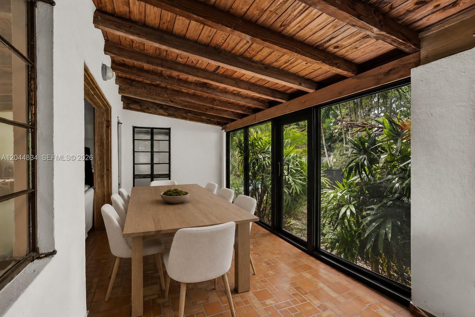 A dining room with a wooden beamed ceiling, terracotta tile floors, and large glass windows — 5390 Sunset Dr, Miami FL 33143, MIAMI, FL