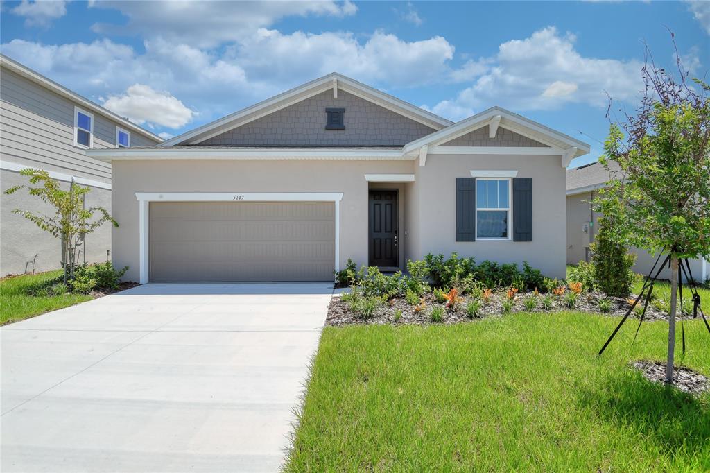 A single-story house with a beige stucco exterior, a two-car garage, and a front lawn — 5147 KINSLEY DRIVE, WINTER HAVEN, FL