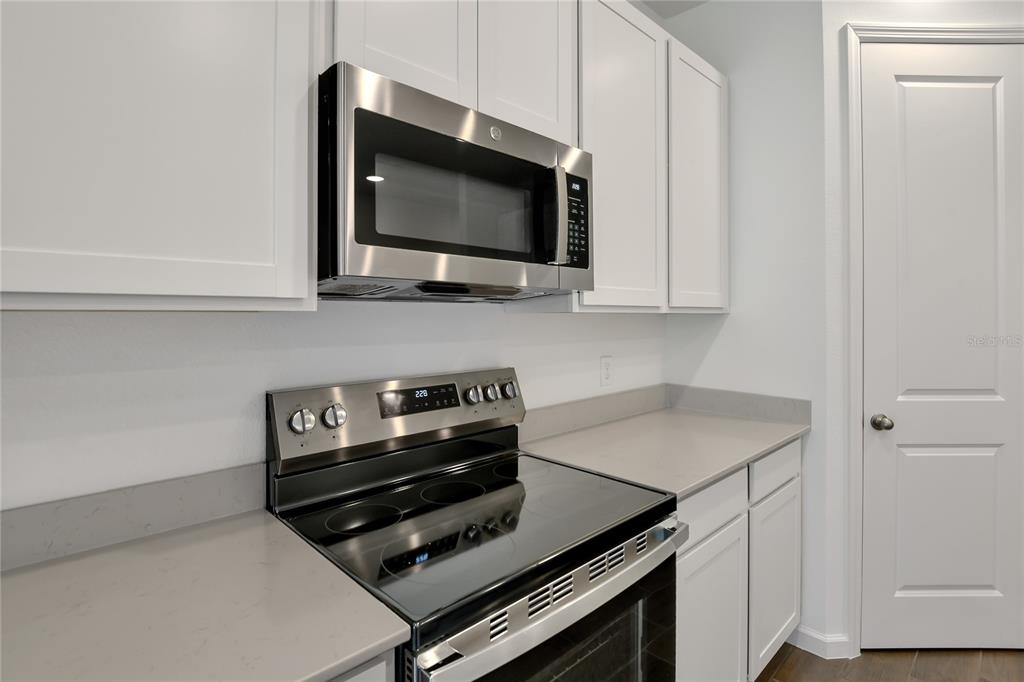 A kitchen features white cabinets, stainless steel appliances, and gray countertops — 5147 KINSLEY DRIVE, WINTER HAVEN, FL