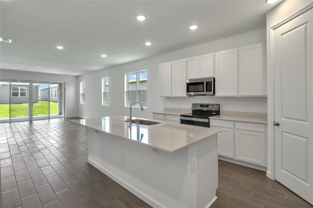 A modern kitchen with white cabinets, a central island, and tile flooring in an open space — 5147 KINSLEY DRIVE, WINTER HAVEN, FL