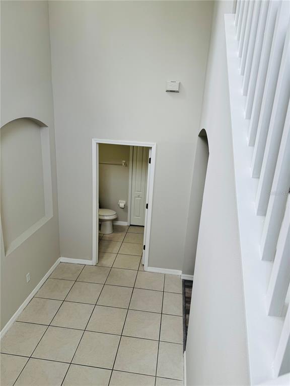 A view from a staircase looking down at a tiled hallway and a small bathroom — 3517 TRAPNELL RIDGE DRIVE, PLANT CITY, FL