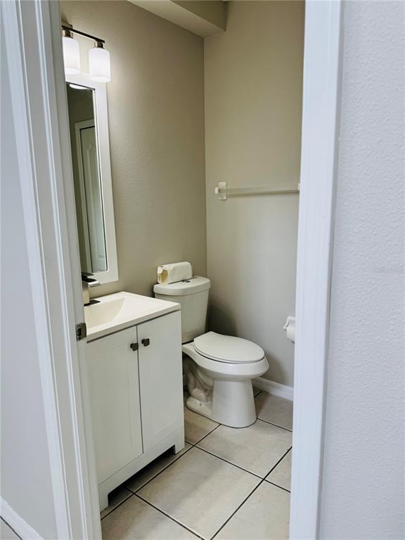 A small bathroom features a white vanity, a toilet, and a wall-mounted mirror — 3517 TRAPNELL RIDGE DRIVE, PLANT CITY, FL
