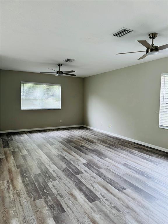 An empty room features light gray walls, wood-look vinyl flooring, and two ceiling fans — 3517 TRAPNELL RIDGE DRIVE, PLANT CITY, FL