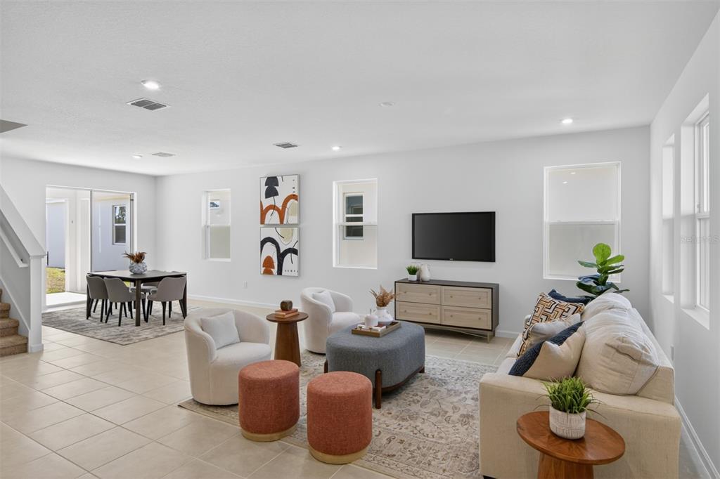 An open-concept living and dining area features tile flooring, a kitchen island, and neutral decor — 13685 SEAGRASS AVENUE, ORLANDO, FL
