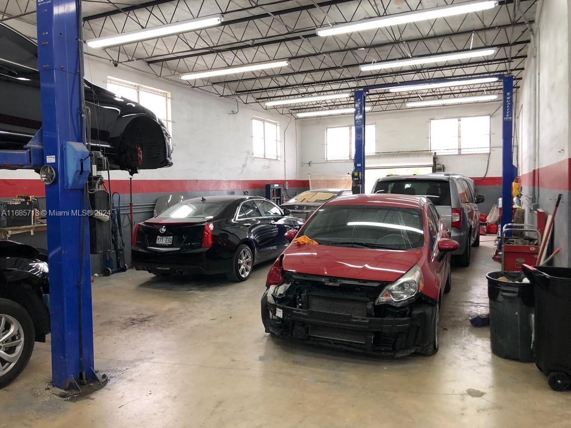 An auto repair shop features multiple vehicle lifts, concrete floors, and several cars being serviced — 707 N Dixie Hwy, Hallandale Beach FL 33009, HALLANDALE BEACH, FL