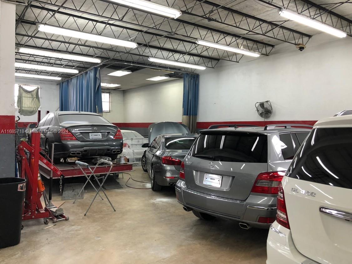 An auto body shop features multiple luxury vehicles parked inside a large industrial workspace — 707 N Dixie Hwy, Hallandale Beach FL 33009, HALLANDALE BEACH, FL