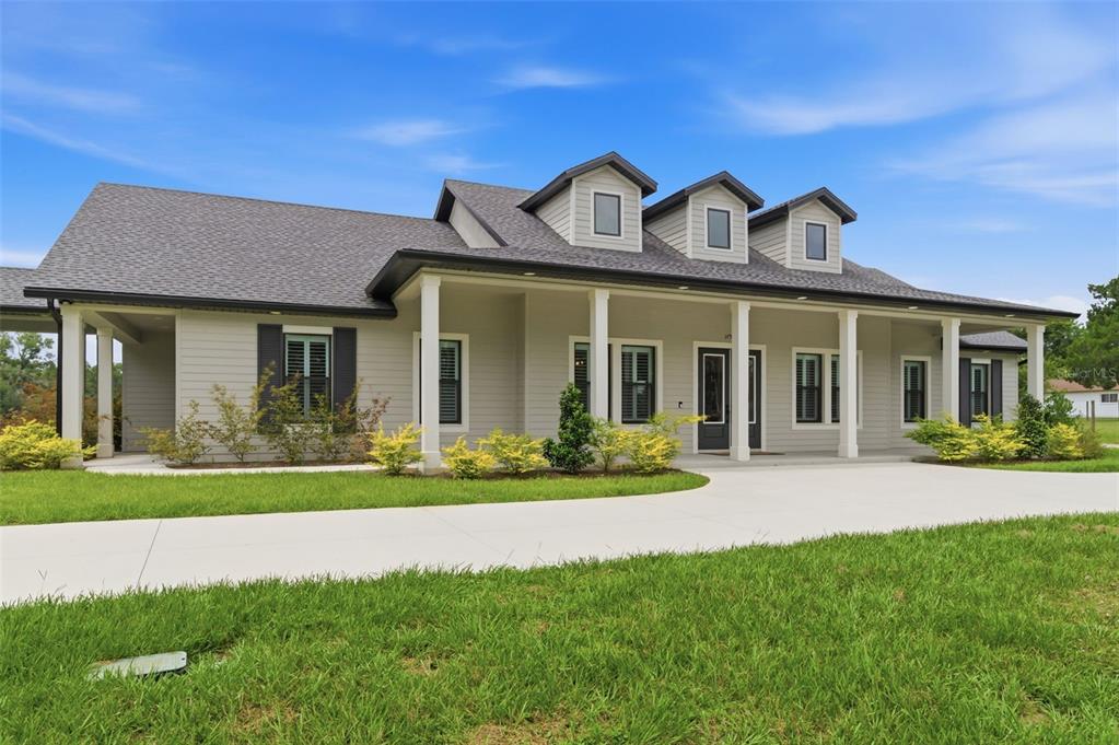A single-story house with light gray siding, a covered front porch, and three roof dormers — 37904 TRILBY ROAD, DADE CITY, FL