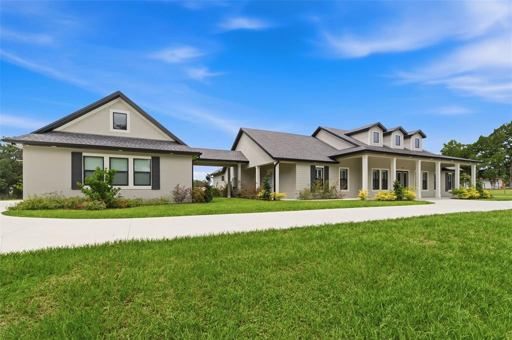 A modern single-story house with a covered walkway connecting two sections and a large lawn — 37904 TRILBY ROAD, DADE CITY, FL