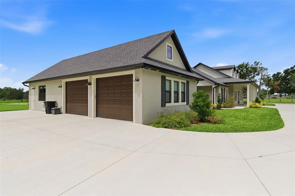 A beige house with a two-car garage, dark brown doors, and a gray shingled roof — 37904 TRILBY ROAD, DADE CITY, FL