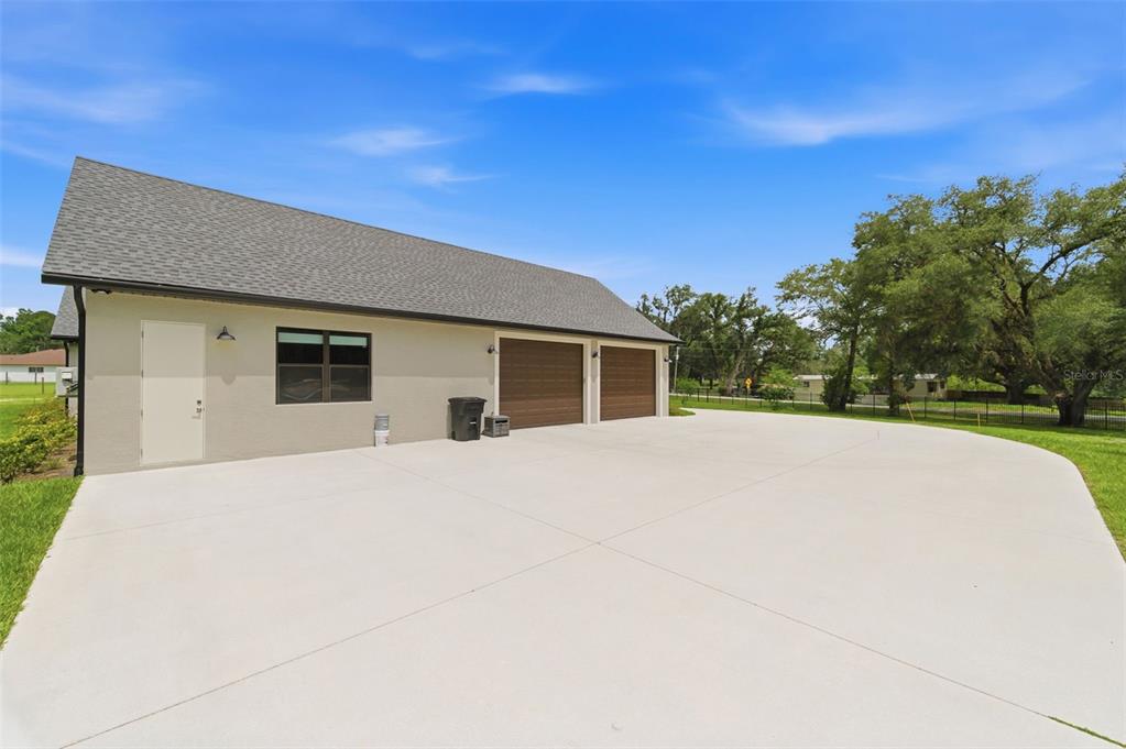 A view of a beige garage exterior with two brown doors and a concrete driveway — 37904 TRILBY ROAD, DADE CITY, FL