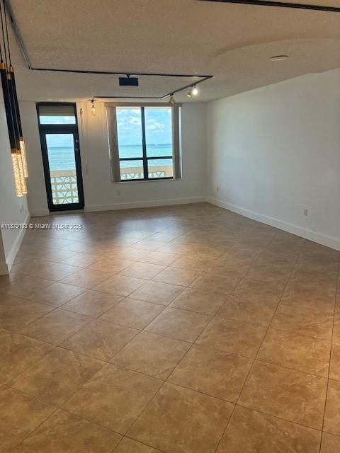 An empty room with tan tile flooring features a large window overlooking the ocean — 10185 Collins Ave # 917, Bal Harbour FL 33154, BAL HARBOUR, FL