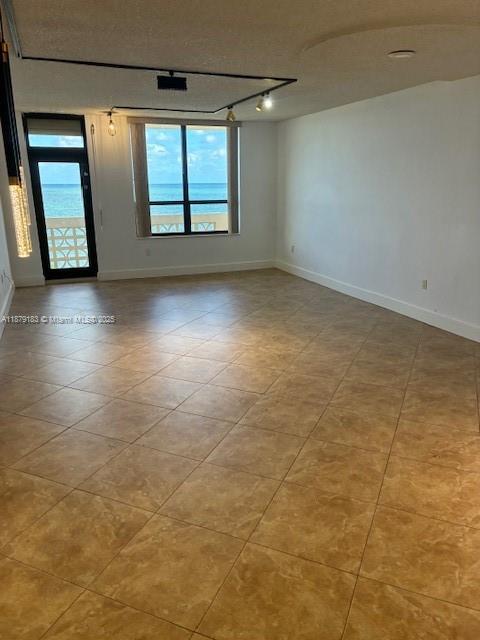 An empty room with tan tile flooring features a large window overlooking the ocean — 10185 Collins Ave # 917, Bal Harbour FL 33154, BAL HARBOUR, FL