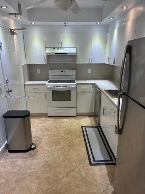 A kitchen features white cabinets, stainless steel appliances, and tan tile flooring — 10185 Collins Ave # 917, Bal Harbour FL 33154, BAL HARBOUR, FL