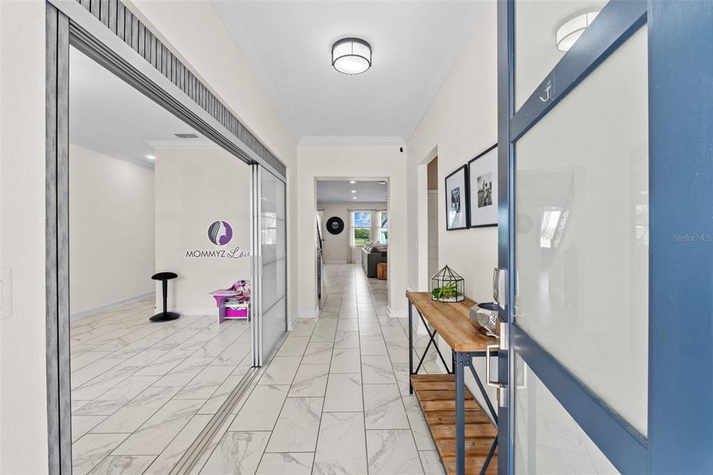 A bright entryway features white marble-look tile flooring, a wooden console table, and sliding glass doors — 14807 WINTER STAY DRIVE, WINTER GARDEN, FL