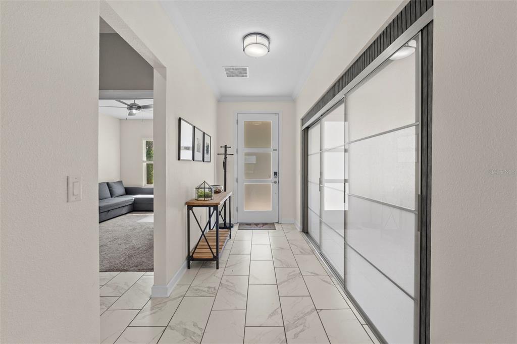 A bright entryway features white tile flooring, a glass-paneled front door, and large sliding closets — 14807 WINTER STAY DRIVE, WINTER GARDEN, FL