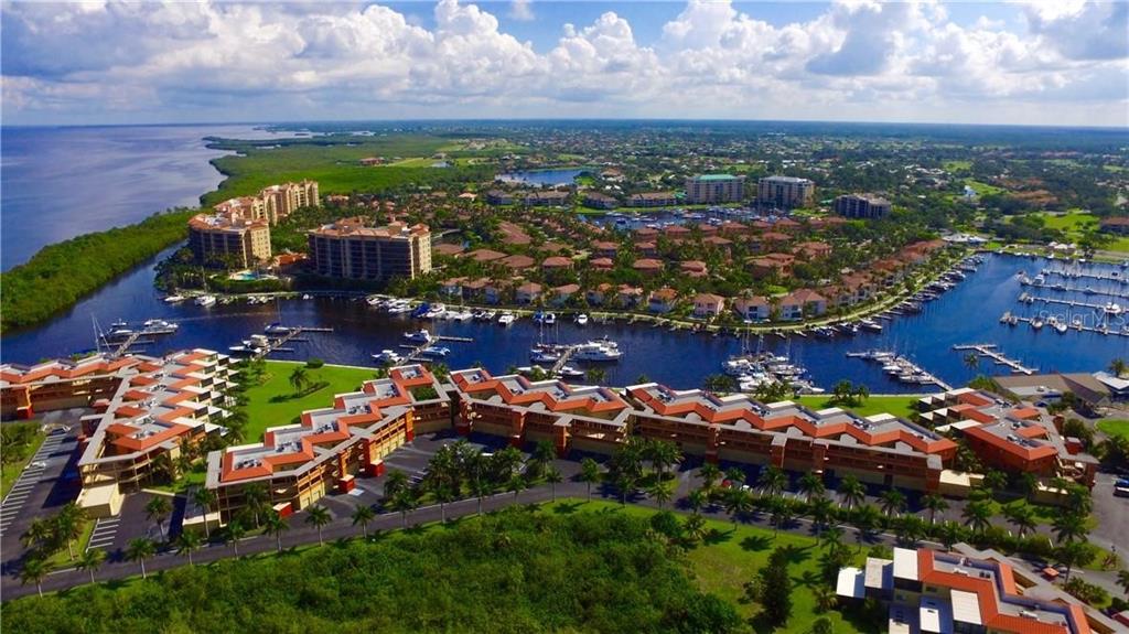 An aerial view shows a waterfront residential complex with boat slips and surrounding green space — 426 GASPAR KEY LANE, PUNTA GORDA, FL