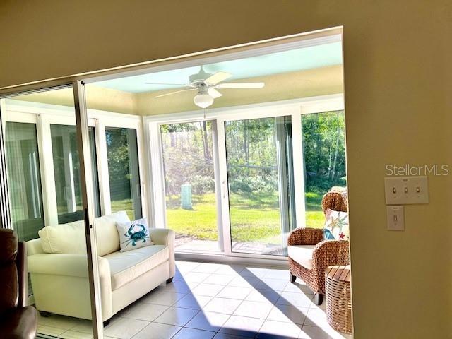 A sunroom with a white sofa, wicker chair, ceiling fan, and sliding glass doors — 426 GASPAR KEY LANE, PUNTA GORDA, FL