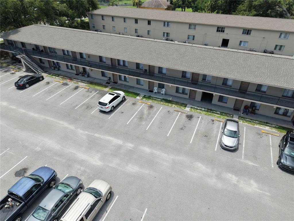 An aerial view shows a multi-story apartment building with a parking lot in front — 6450 78TH AVENUE N UNIT 38, PINELLAS PARK, FL