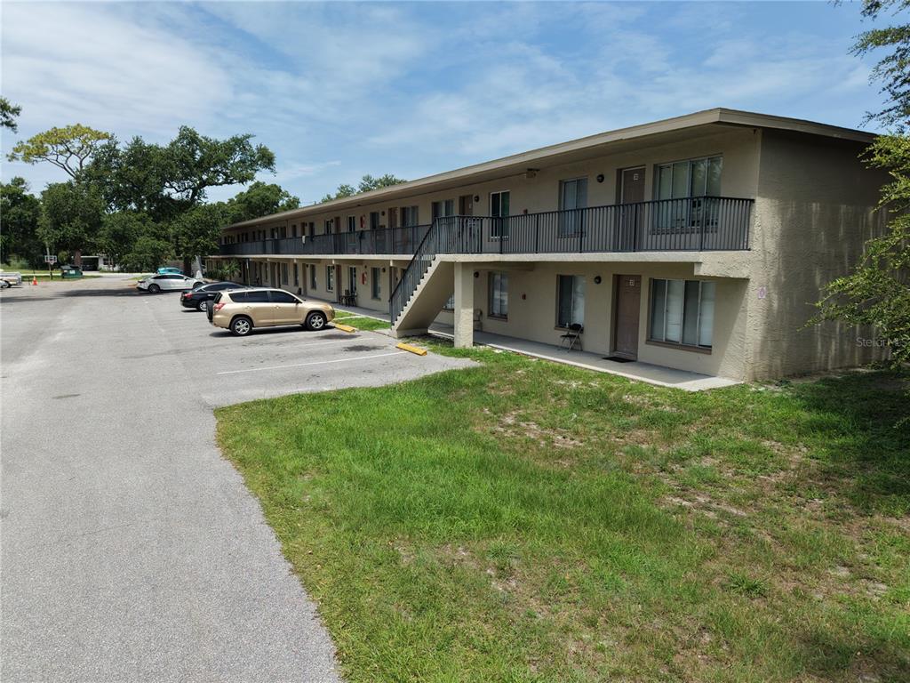 A two-story apartment building with exterior walkways and a parking lot in front — 6450 78TH AVENUE N UNIT 38, PINELLAS PARK, FL