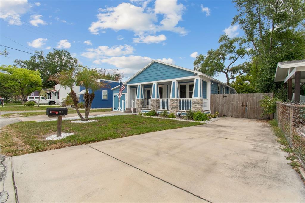 A blue house with a front porch and a concrete driveway under a cloudy sky — 507 W PARIS STREET, TAMPA, FL