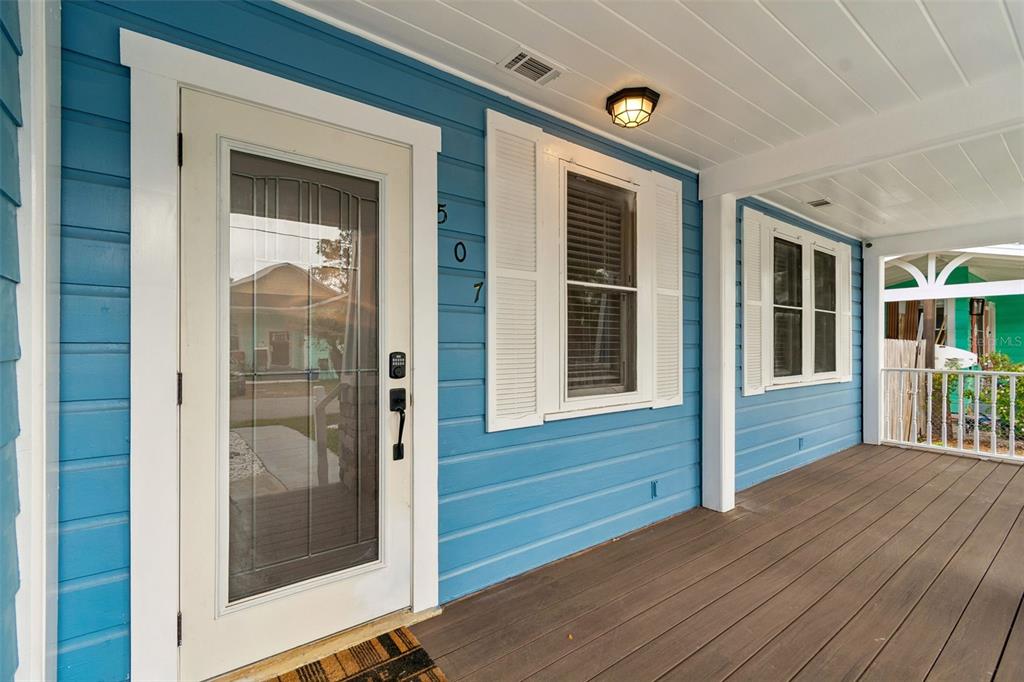 A blue-sided house features a covered front porch with a glass-paneled door and windows — 507 W PARIS STREET, TAMPA, FL