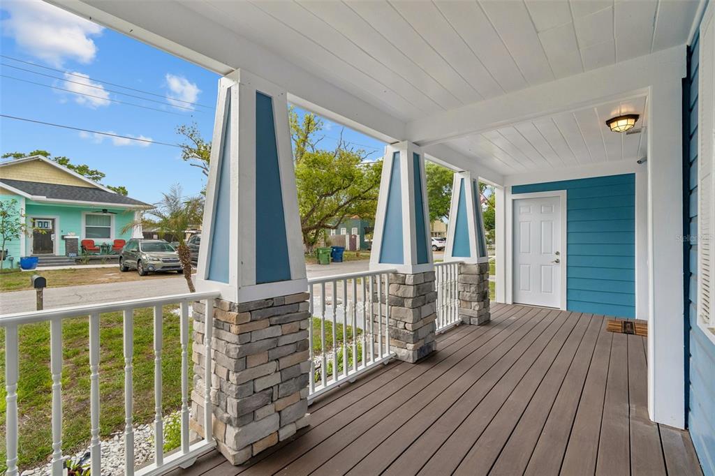 A covered front porch features stone-based columns, white railings, and a blue-accented exterior wall — 507 W PARIS STREET, TAMPA, FL