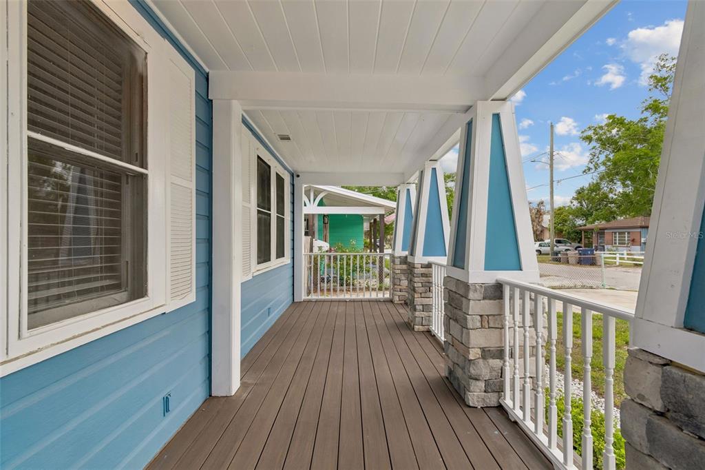 A covered front porch features blue siding, stone-based columns, and a wooden deck — 507 W PARIS STREET, TAMPA, FL