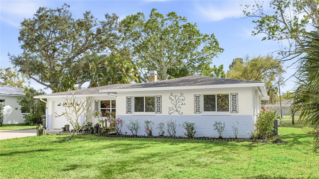 A single-story house with a white and light blue exterior, a chimney, and a lawn — 3236 ASHTON ROAD, SARASOTA, FL