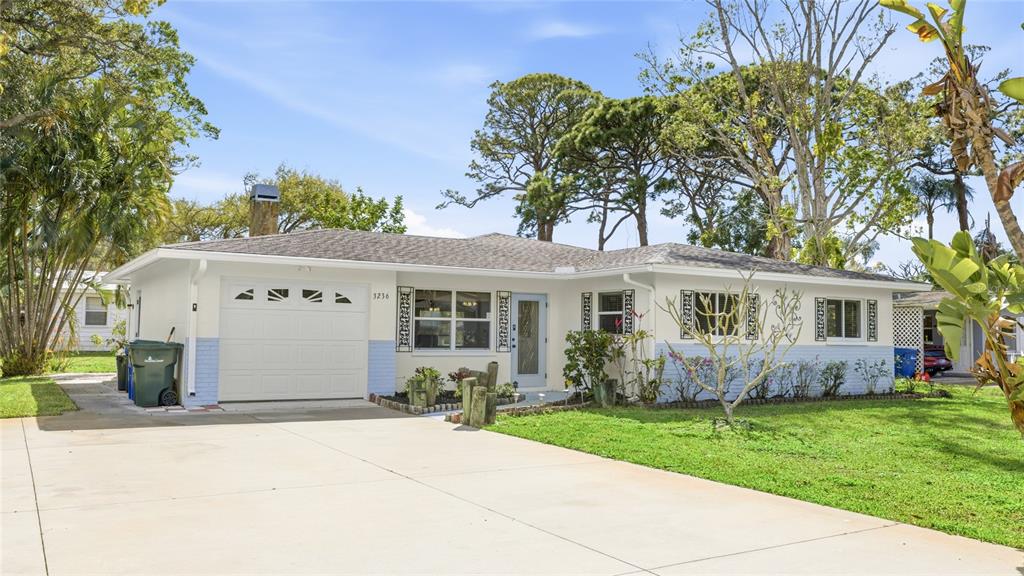 A single-story house with a white and light blue exterior, a garage, and a concrete driveway — 3236 ASHTON ROAD, SARASOTA, FL