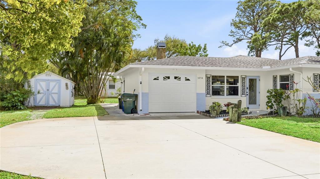 A single-story house with a white garage, light blue accents, and a detached storage shed — 3236 ASHTON ROAD, SARASOTA, FL