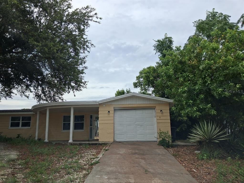 A single-story house with a yellow exterior, a front porch, and an attached garage — 4926 COLONNADE AVENUE, HOLIDAY, FL