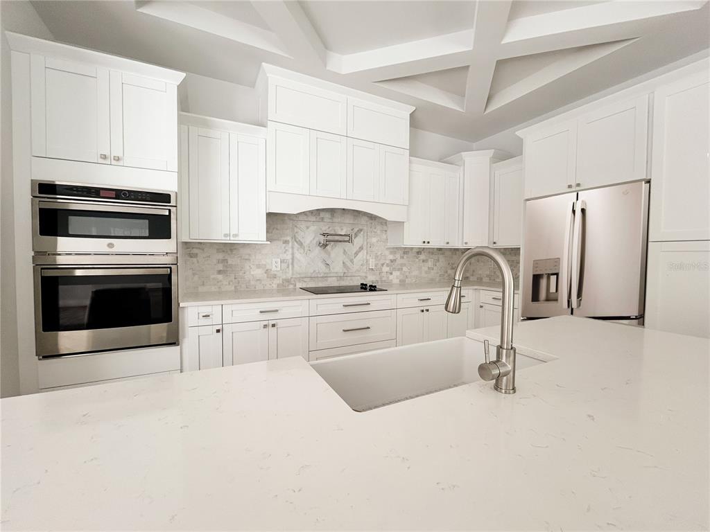 A white kitchen features a large island, stainless steel appliances, and a coffered ceiling — 407 GEORGIA AVENUE, CRYSTAL BEACH, FL