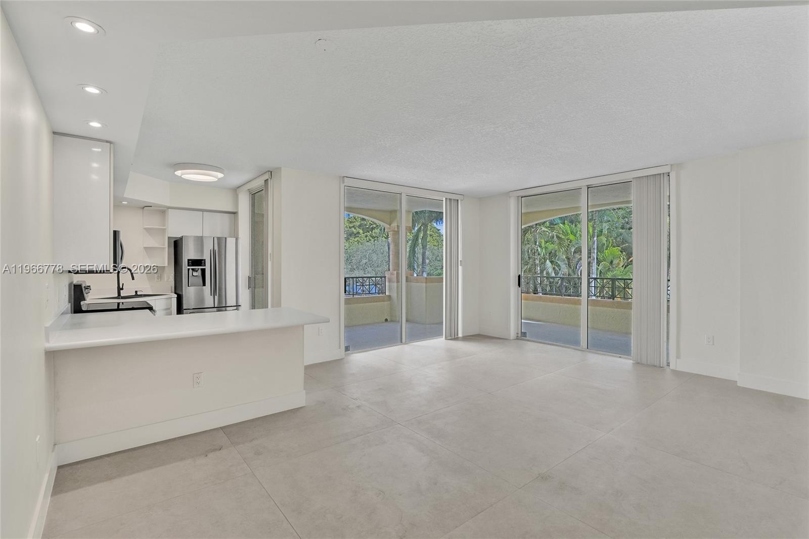 A bright, open-concept living area features white cabinetry, a kitchen island, and sliding glass doors — 1834 Brickell Ave # 31, Miami FL 33129, MIAMI, FL