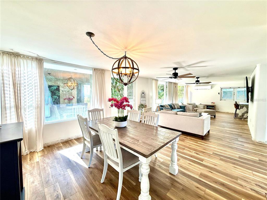 A dining area with a wooden table and orb chandelier opens into a living room — 5 BATEY OESTE UNIT 14, LUQUILLO, PR