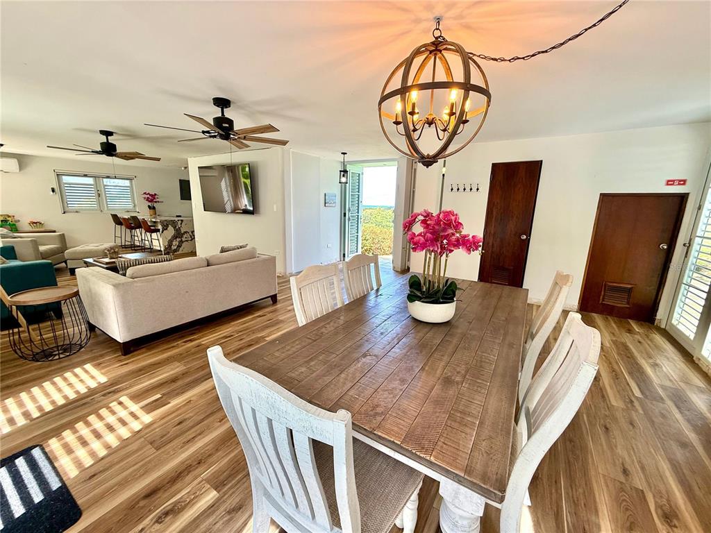A dining area with a wooden table and chairs opens into a living room space — 5 BATEY OESTE UNIT 14, LUQUILLO, PR