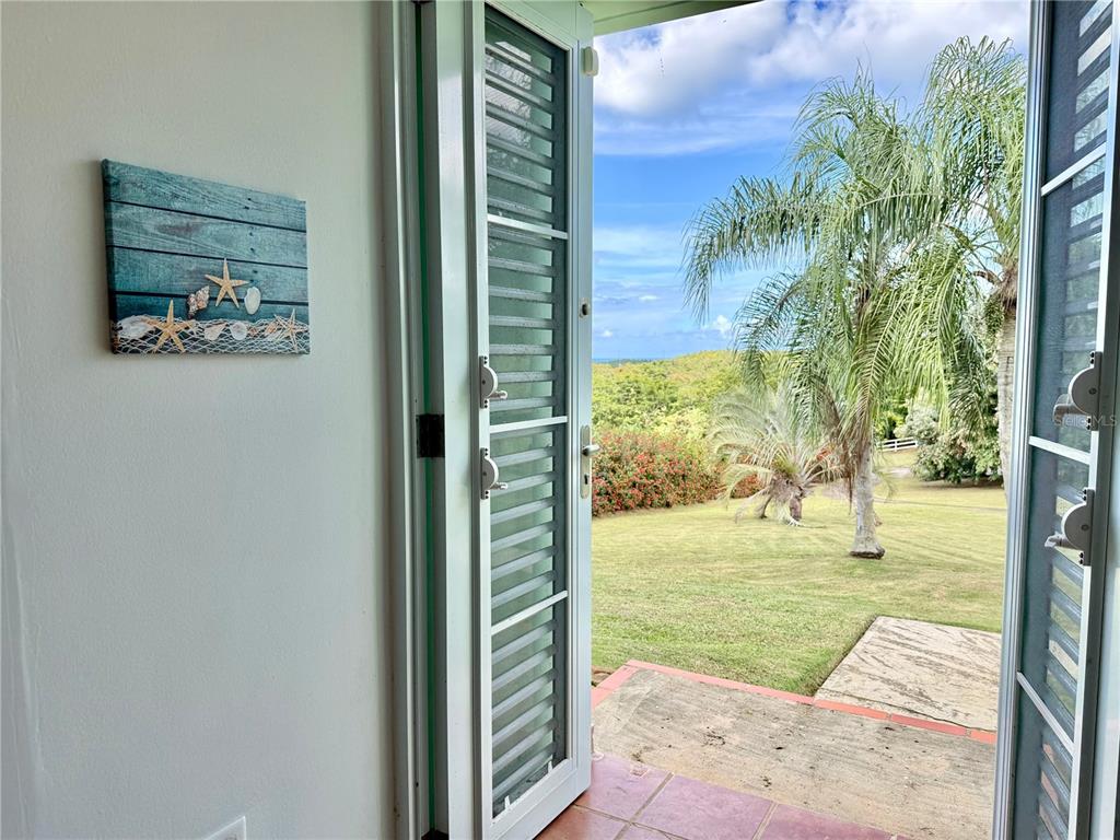 A view from an interior room through open French doors to a grassy yard — 5 BATEY OESTE UNIT 14, LUQUILLO, PR