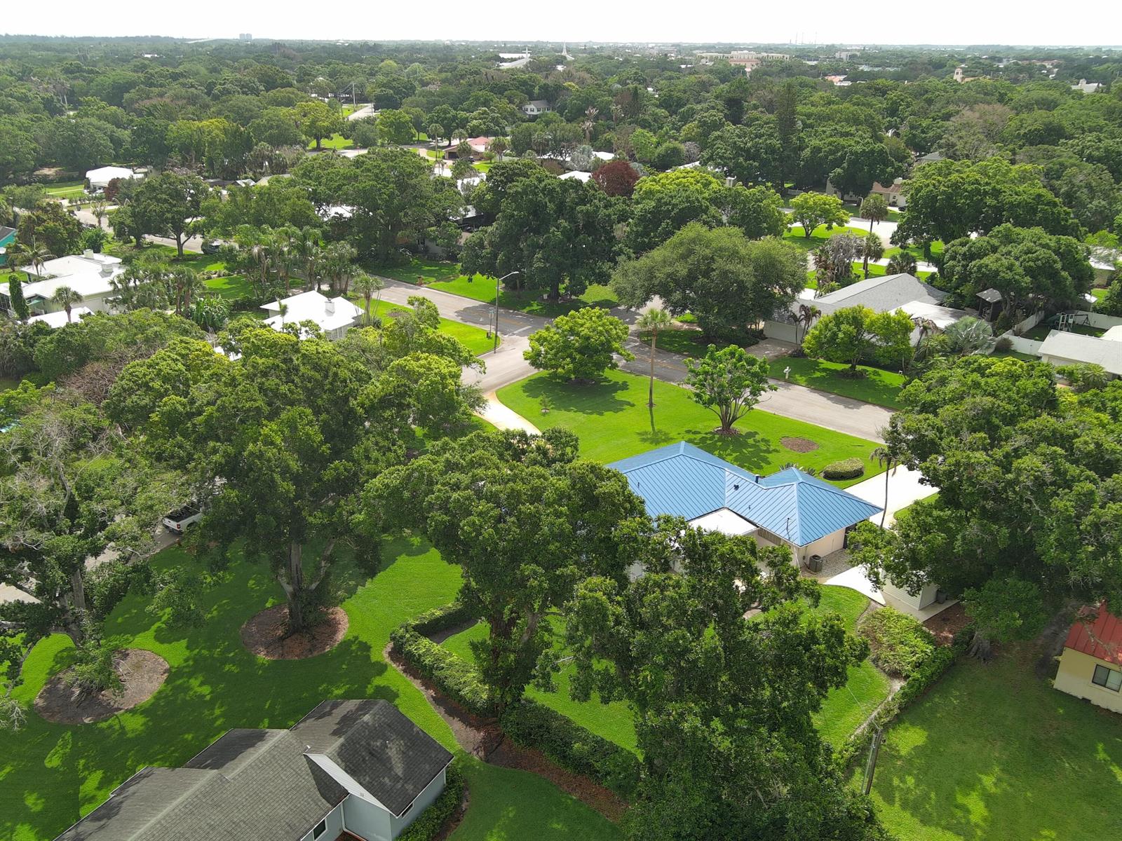 An aerial view shows a residential neighborhood with lush trees and houses with metal roofs — 2301 Avalon Avenue, Vero Beach FL 32960, VERO BEACH, FL