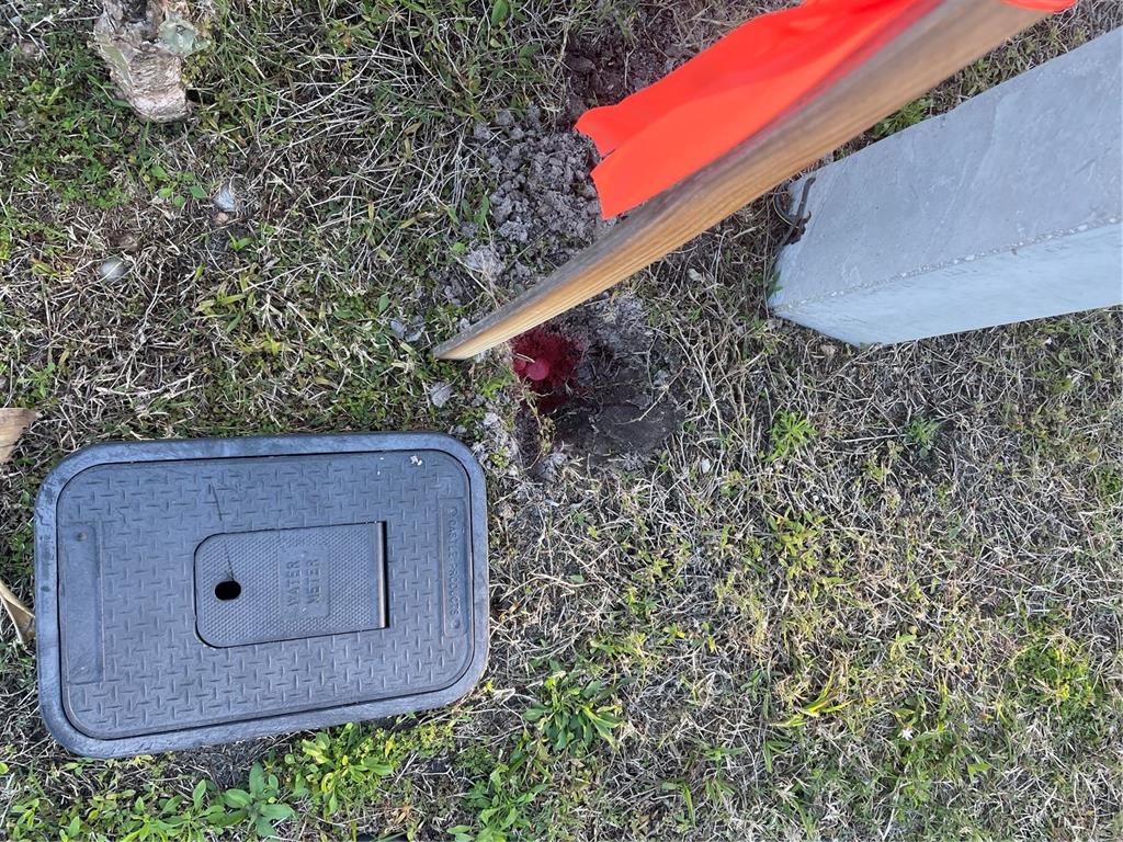 A water meter box sits in the grass next to a wooden stake with orange flagging — 9098 KESTRAL CIRCLE, ENGLEWOOD, FL