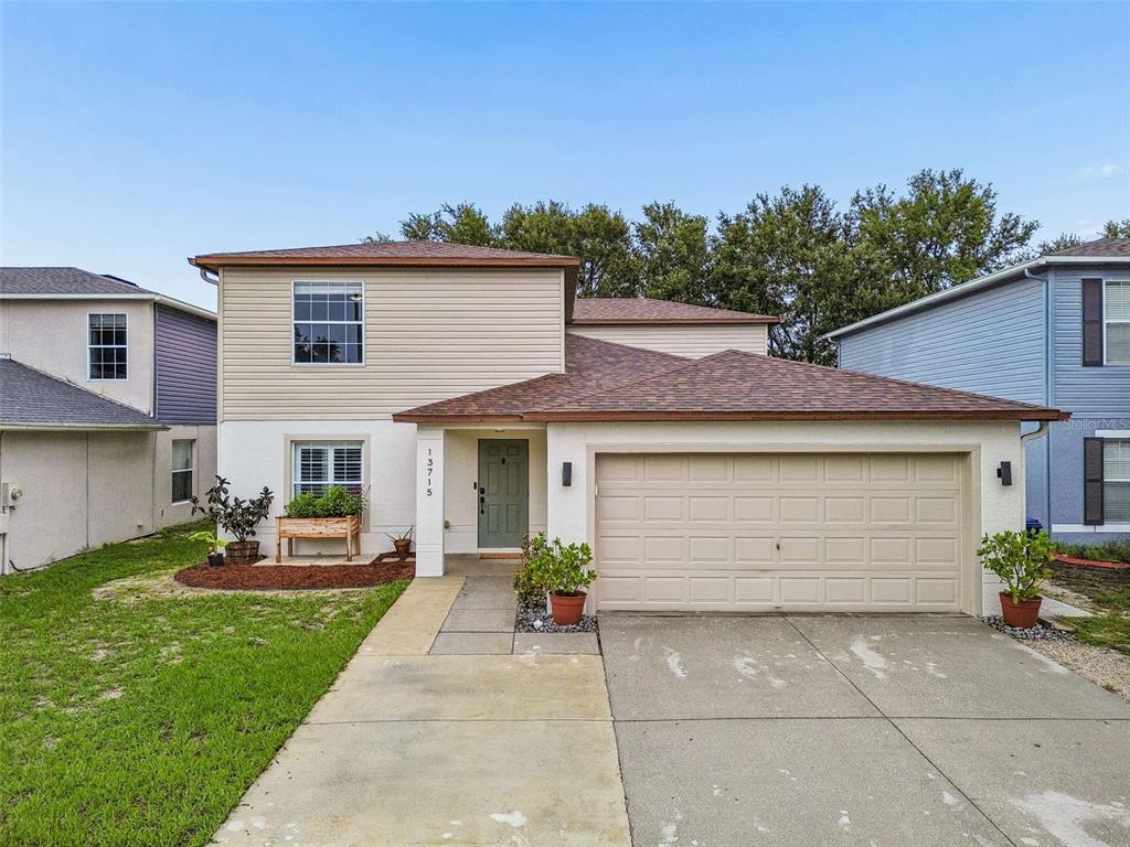 A two-story house with beige siding, a white stucco lower level, and a two-car garage — 13715 TRAMORE DRIVE, ODESSA, FL