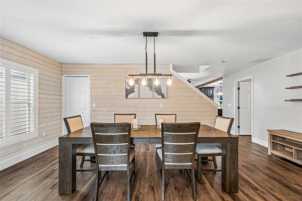 A dining room features a wooden table, six chairs, a light fixture, and shiplap walls — 13715 TRAMORE DRIVE, ODESSA, FL