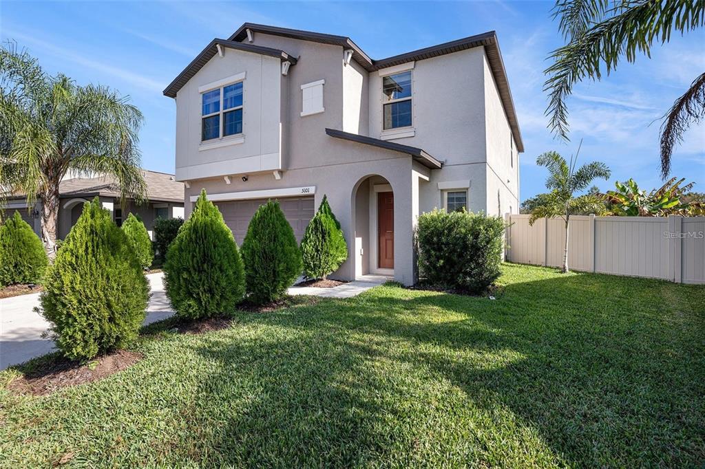 A two-story suburban house with a tan stucco exterior, a garage, and a front lawn — 5101 SABLE CHIME DRIVE, WIMAUMA, FL