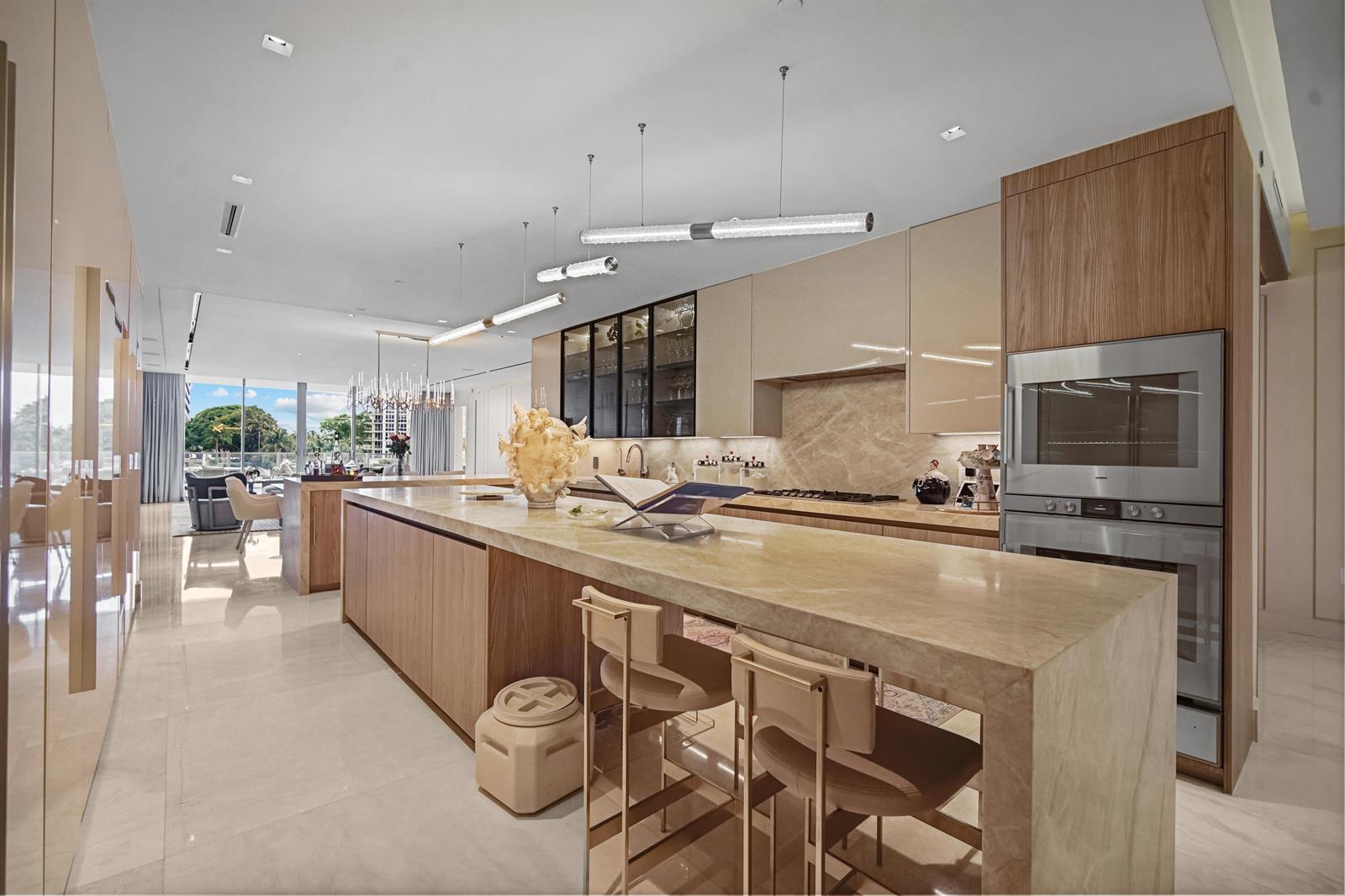 A modern kitchen features a large stone island, wood cabinetry, and stainless steel appliances — 725 S Ocean Boulevard # 206, Boca Raton FL 33432, BOCA RATON, FL