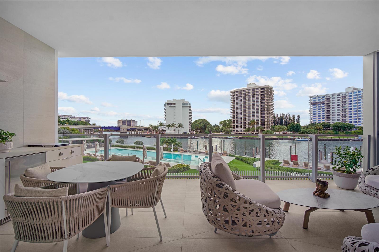 A covered balcony features outdoor furniture, a dining table, and views of a pool and waterway — 725 S Ocean Boulevard # 206, Boca Raton FL 33432, BOCA RATON, FL