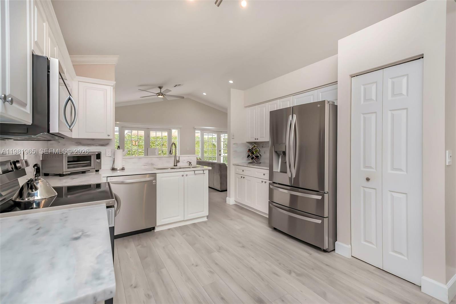 A kitchen with white cabinets, stainless steel appliances, and light wood-look flooring — 11030 Harbour Springs Cir, Boca Raton FL 33428, BOCA RATON, FL