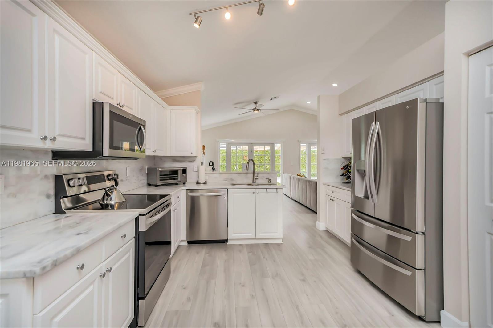 A modern kitchen features white cabinets, marble-style countertops, and stainless steel appliances — 11030 Harbour Springs Cir, Boca Raton FL 33428, BOCA RATON, FL