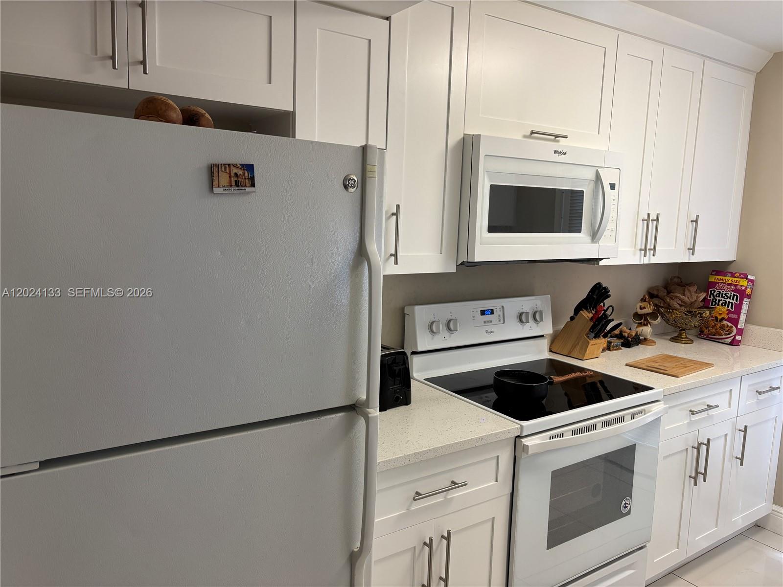 A kitchen features white cabinets, a white refrigerator, a microwave, and a black electric stove — 10806 N Kendall Dr # 26, Miami FL 33176, MIAMI, FL