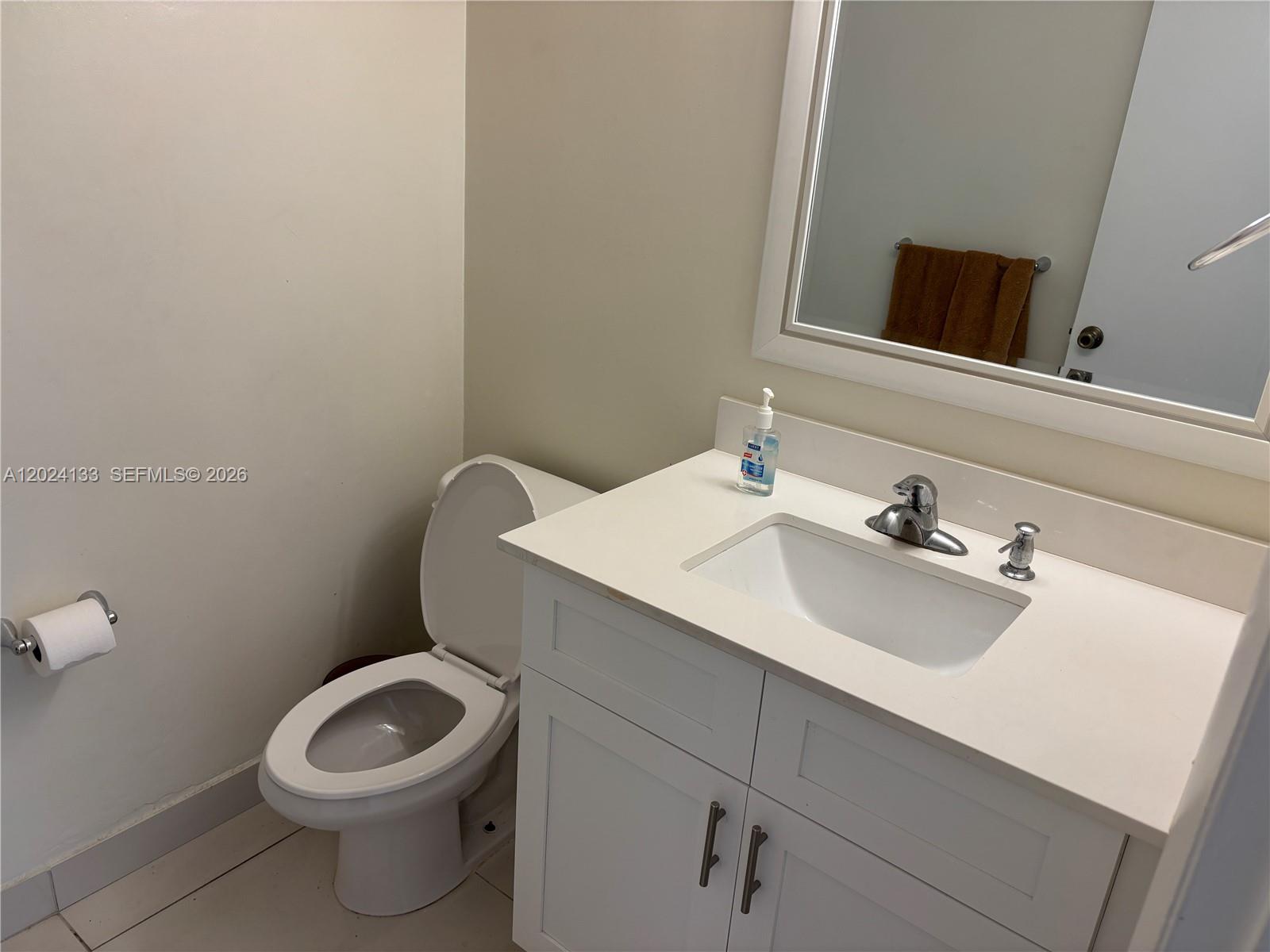 A bathroom features a white vanity with a sink, a toilet, and a wall mirror — 10806 N Kendall Dr # 26, Miami FL 33176, MIAMI, FL