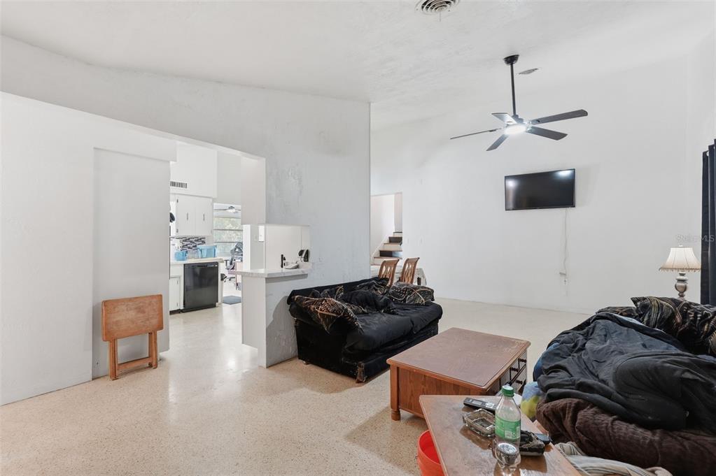 A living room with white walls, a ceiling fan, and a view into the kitchen — 11830 86TH AVENUE, SEMINOLE, FL