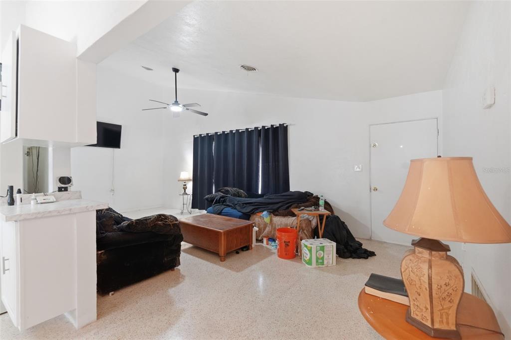 A living room with white walls, terrazzo flooring, a ceiling fan, and dark curtains — 11830 86TH AVENUE, SEMINOLE, FL