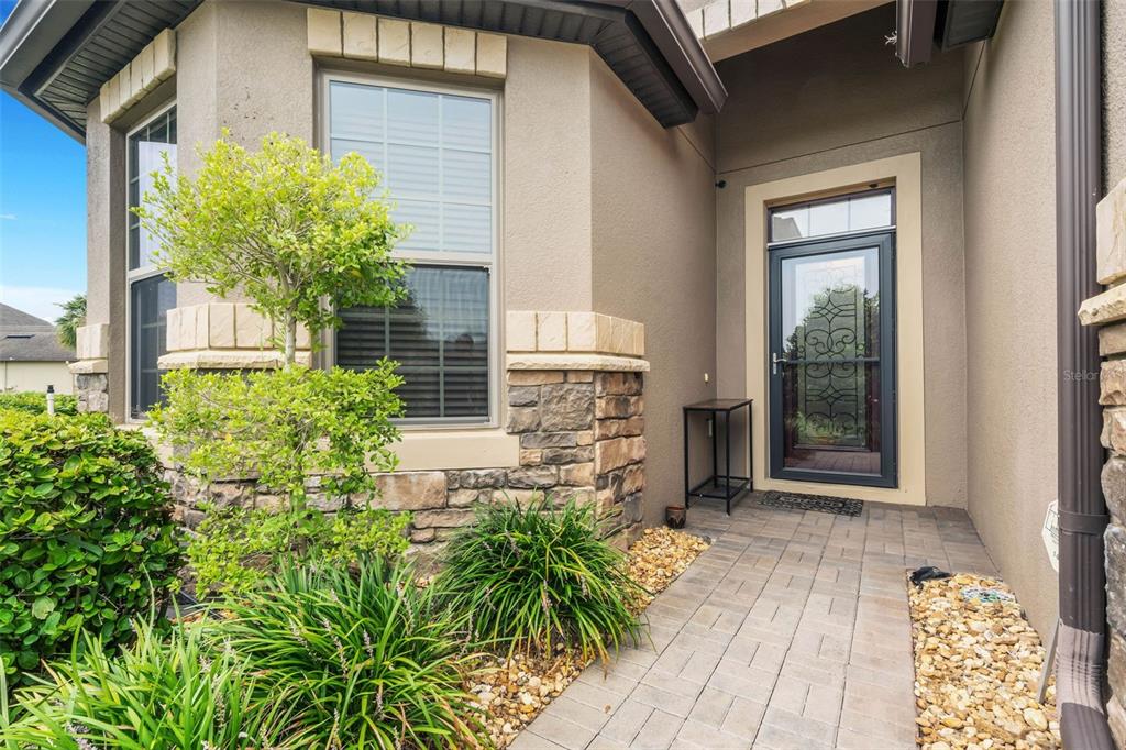 A paved walkway leads to a front entrance with a decorative glass door and stone accents — 100 CASTELLON COURT, DAVENPORT, FL